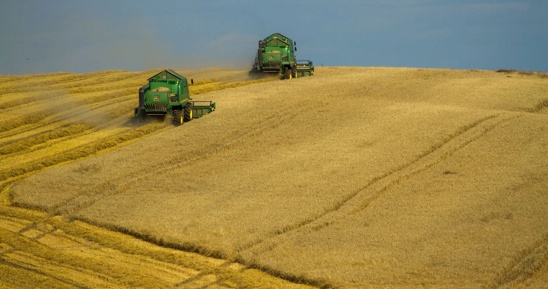 Combine harvesters working across a large tillage field.